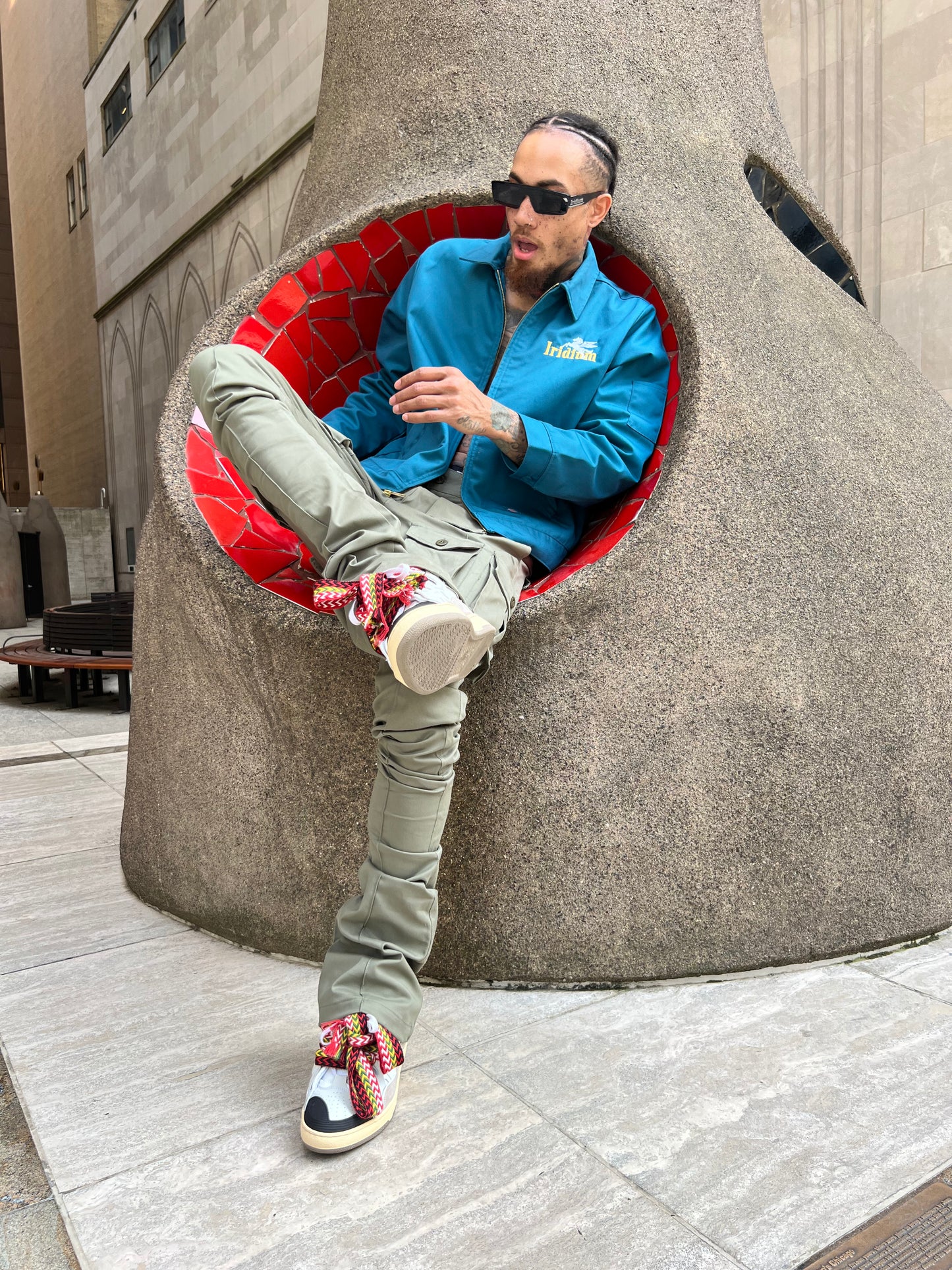 Model seated in a red chair wearing Green Stacked Cargo Pants