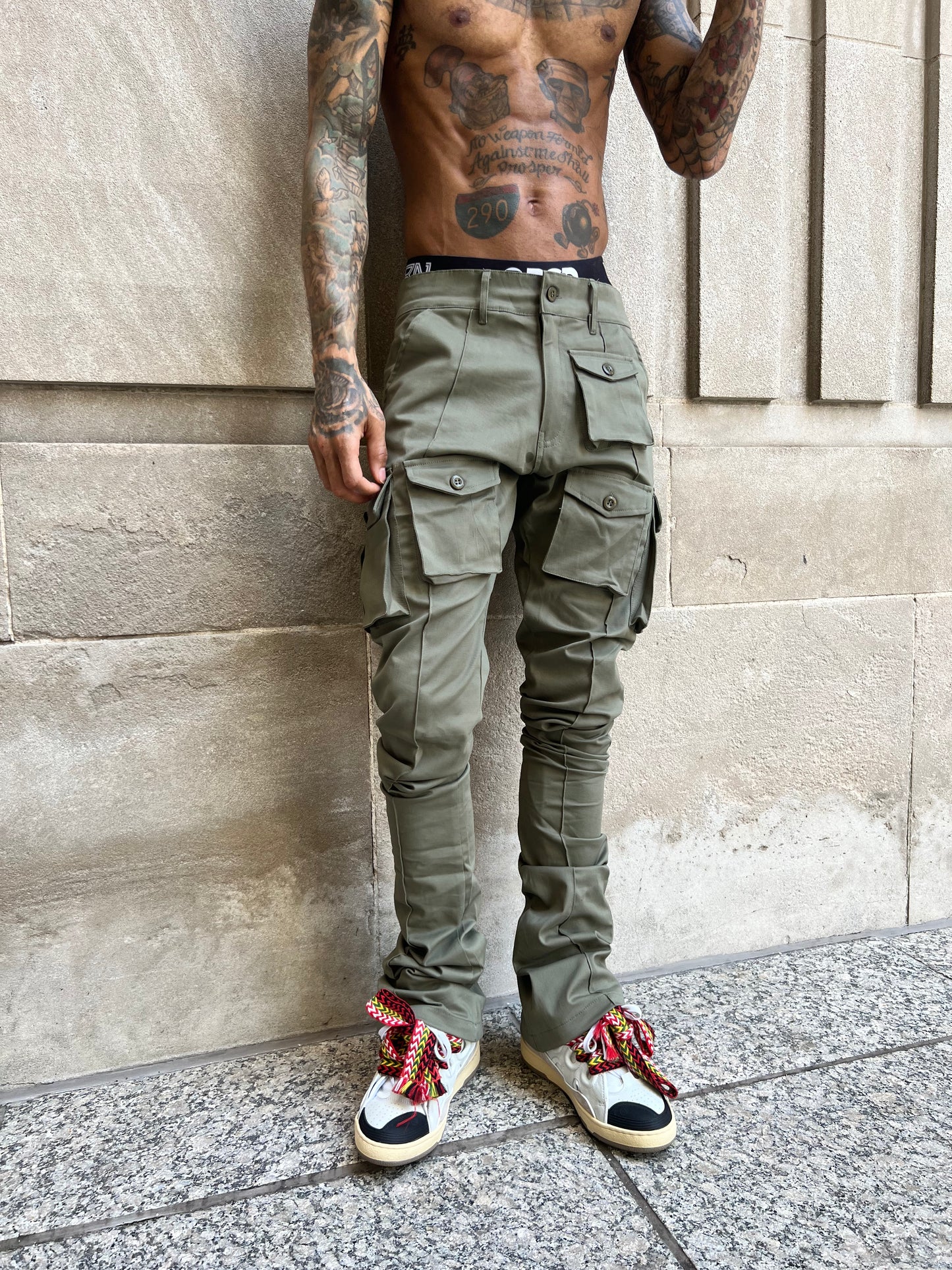Full front view of Iridium Green Stacked Cargo Pants against a stone wall