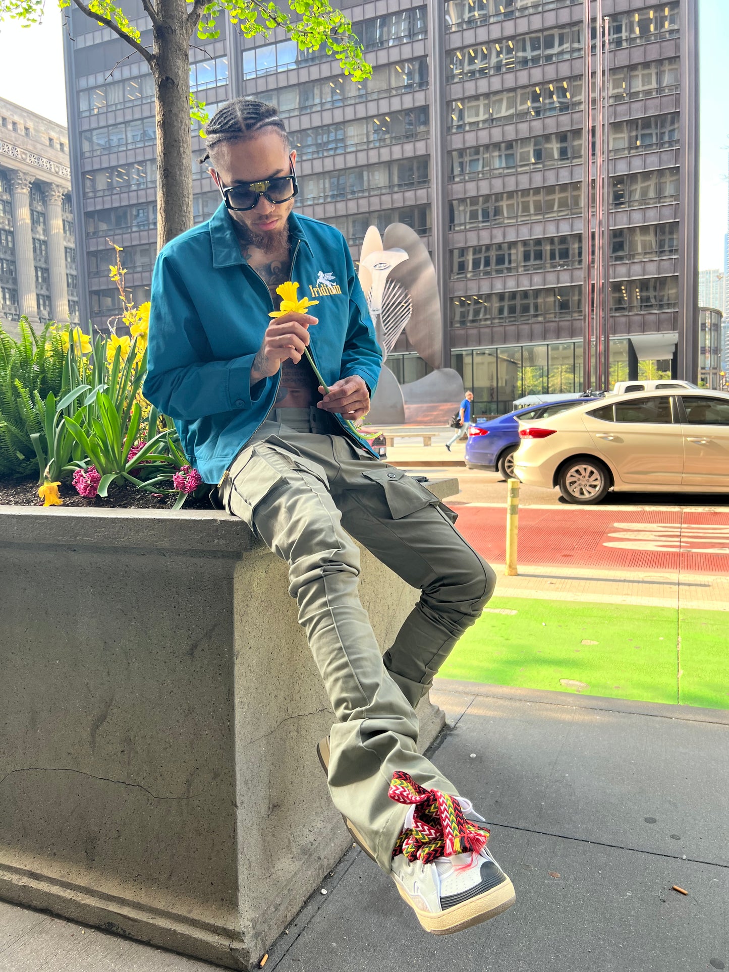 Model seated outdoors wearing Iridium Green Stacked Cargo Pants