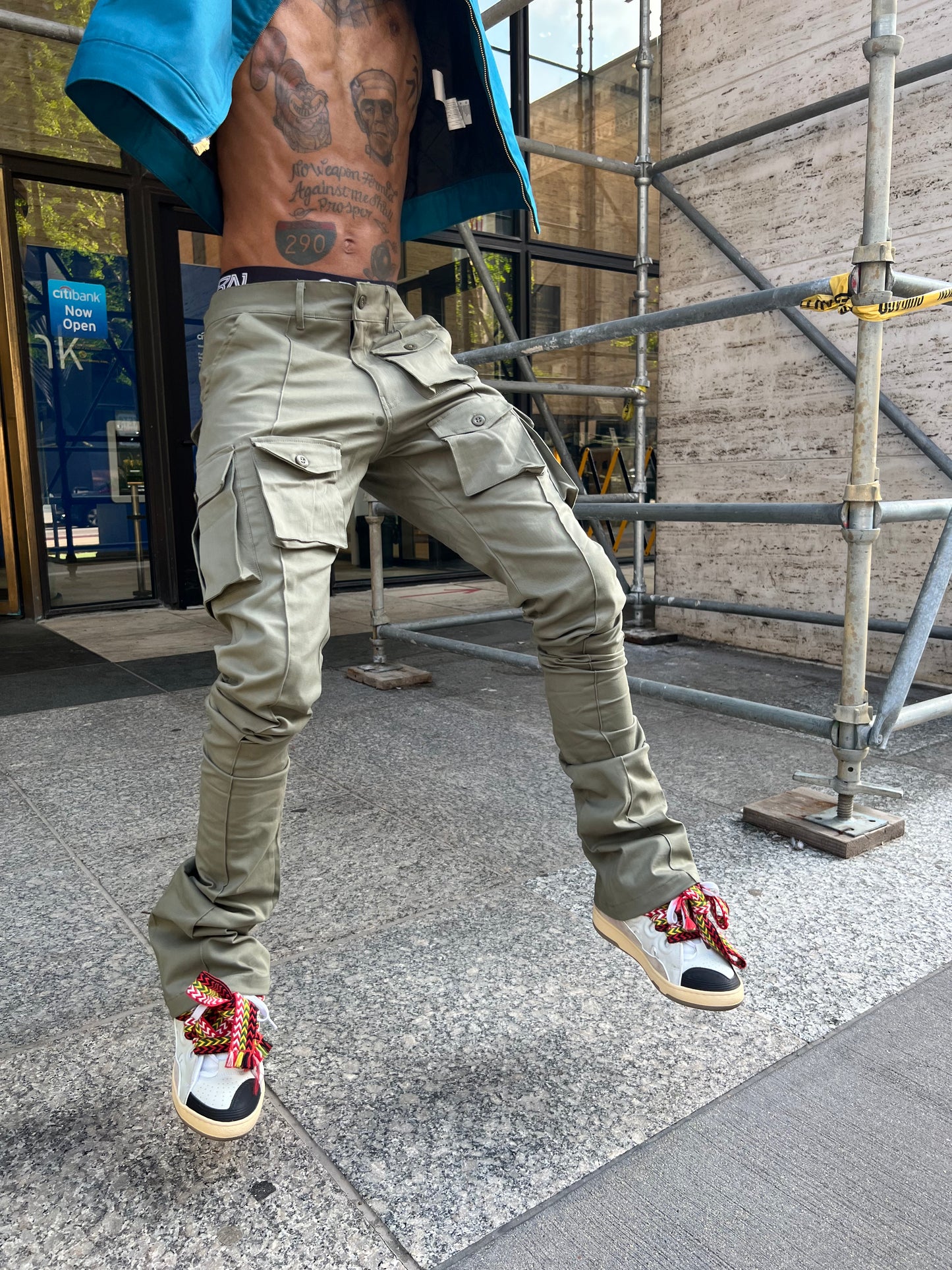 Front view of a model wearing Green Stacked Cargo Pants under city scaffolding
