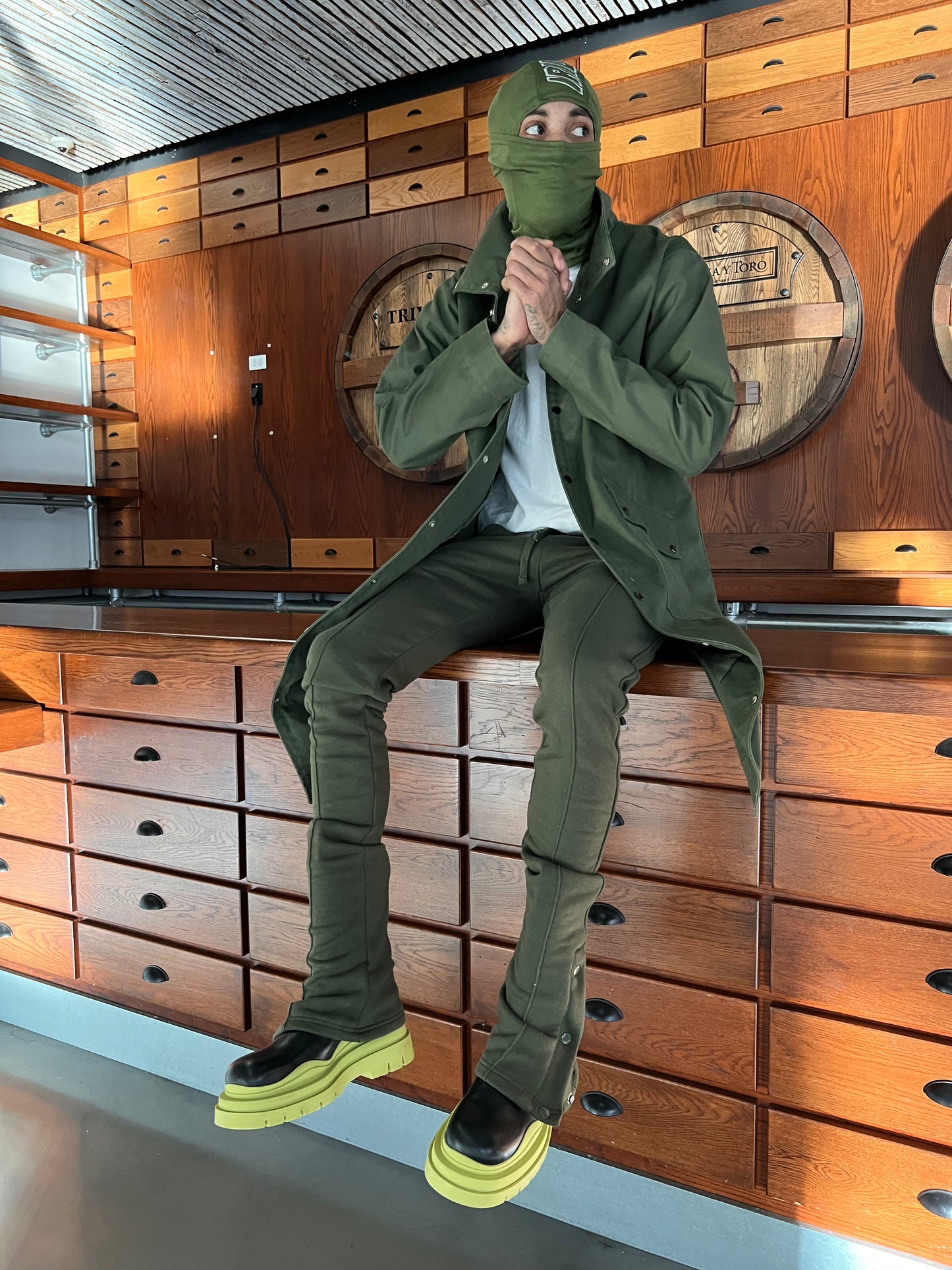 Model seated at a counter wearing Green Stacked Joggers